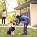 PURCOR Pest Solutions agent petting dog of two homeowners in front yard.