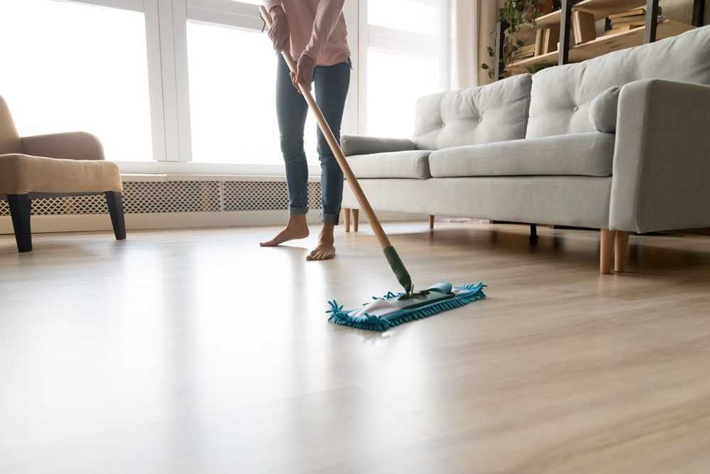 a barefoot woman is cleaning the floor of her living room with a mop