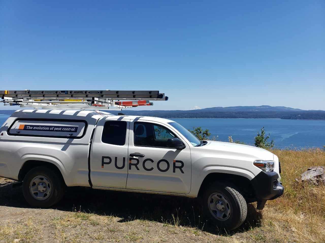 PURCOR Pest Control truck parked in front a lake.