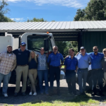 A group of eight people stand in front of two Choice Pest Management work trucks for standard pest control.