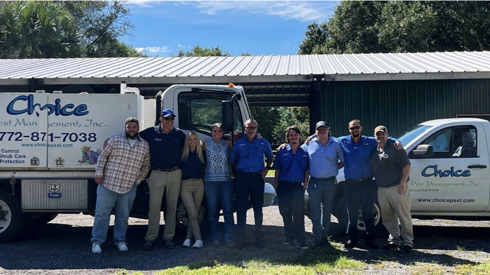A group of eight people stand in front of two Choice Pest Management work trucks for standard pest control.